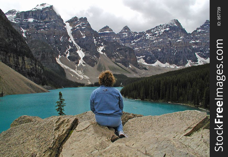 This image of the young lady relaxing and checking out the mountains and lake was taken in Canada. This image of the young lady relaxing and checking out the mountains and lake was taken in Canada.