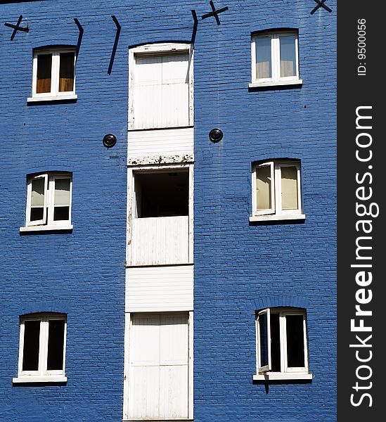 Contrasting white windows against a bright blue wall on an old building. Architectural details. Contrasting white windows against a bright blue wall on an old building. Architectural details.