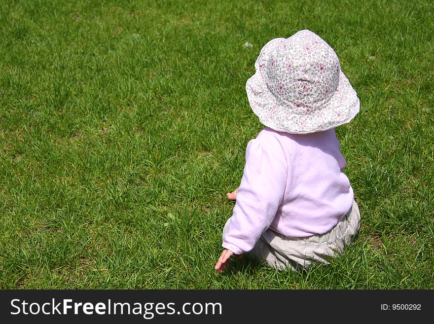 Summer shot - little girl with panama sitting on green grass. Summer shot - little girl with panama sitting on green grass