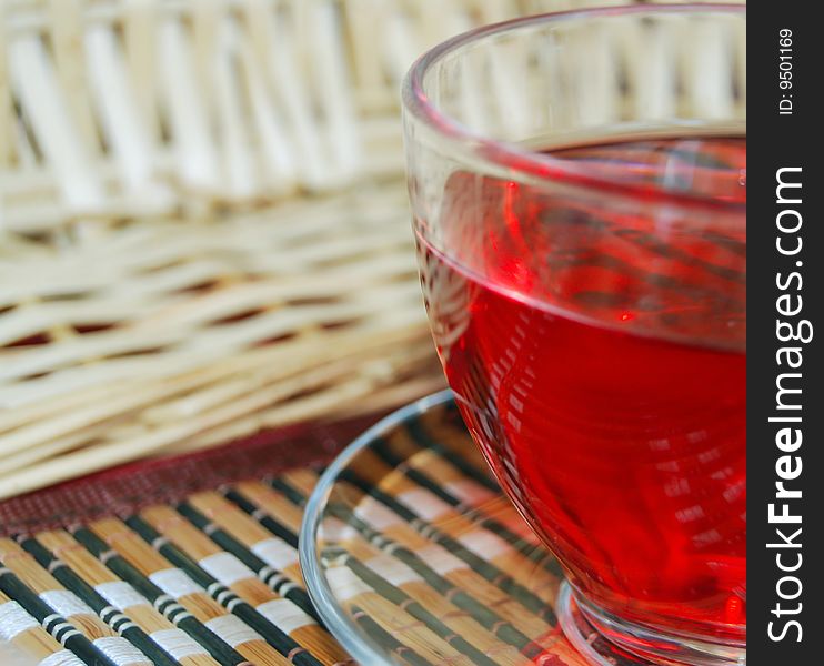 Transparent cup of tea on a table-cloth in a cage. Small basket. Transparent cup of tea on a table-cloth in a cage. Small basket