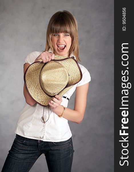 Cowgirl in a hat on a grey background possing in a studio. Cowgirl in a hat on a grey background possing in a studio