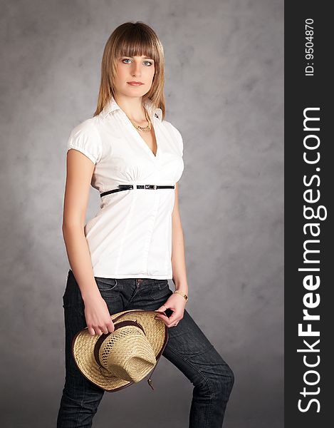 Cowgirl in a hat on a grey background possing in a studio. Cowgirl in a hat on a grey background possing in a studio