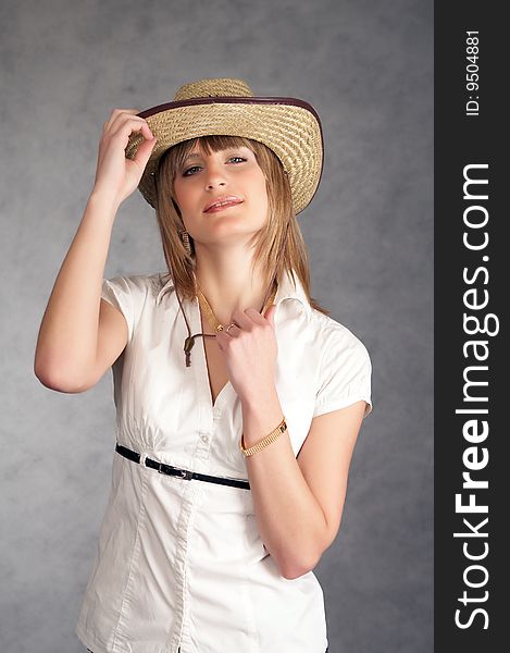 Cowgirl in a hat on a grey background possing in a studio