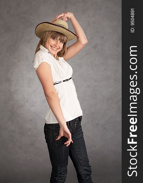 Cowgirl in a hat on a grey background possing in a studio