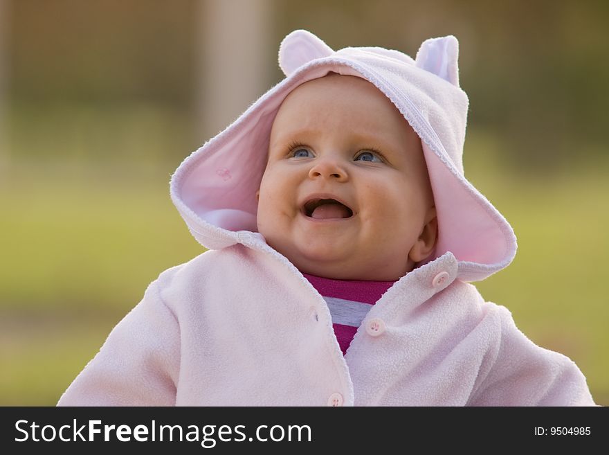 Happy little babygirl sitting on the grass with blurred background. Happy little babygirl sitting on the grass with blurred background.