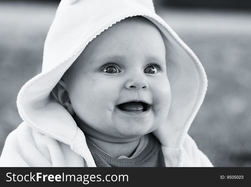 Happy little babygirl sitting on the grass with blurred background. Blue toned image. Happy little babygirl sitting on the grass with blurred background. Blue toned image.