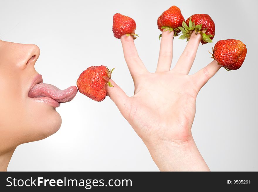 Sweet caucasian girl eating strawberries picked on fingertips