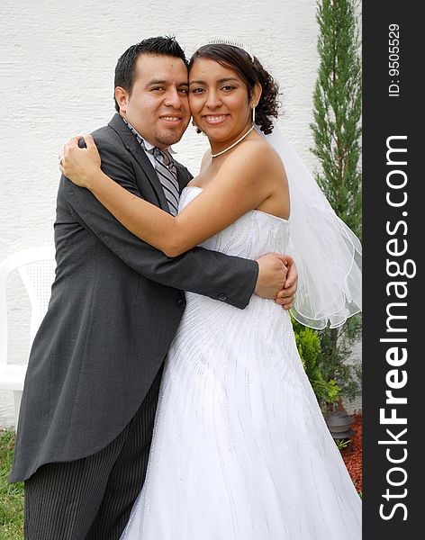 Attractive Hispanic Bride and Groom embrace