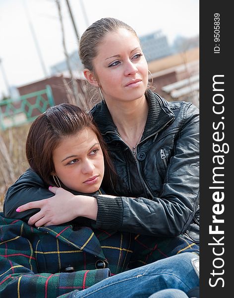 Two young girls relax on a bench in a park. Two young girls relax on a bench in a park