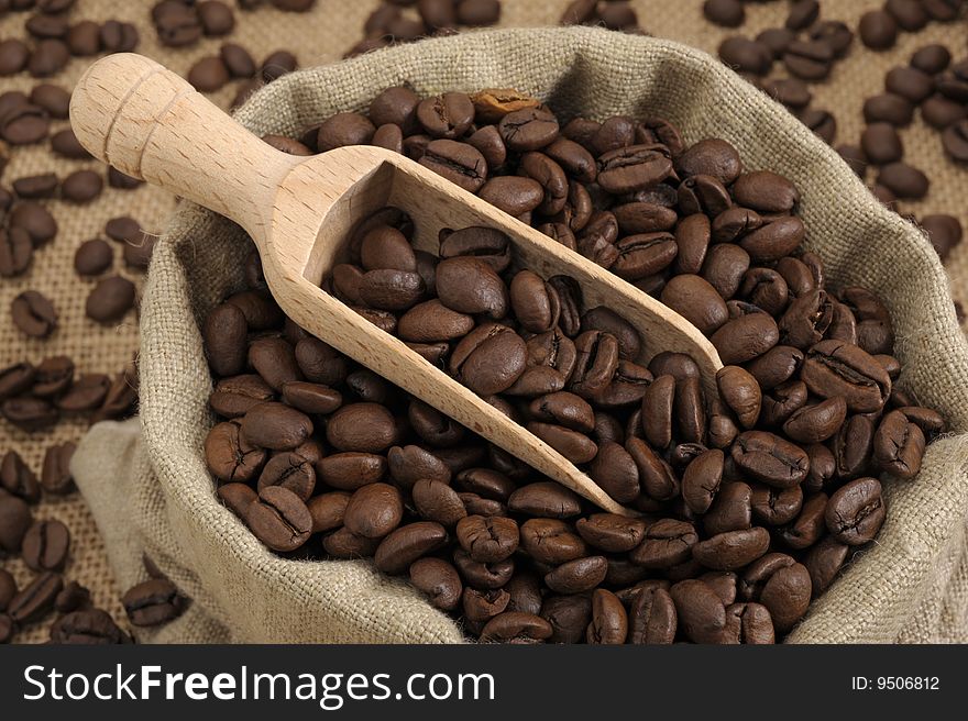 Coffee beans in an natural bag with a wooden scoop