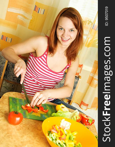 Beautiful young woman at home in the kitchen making salad. Beautiful young woman at home in the kitchen making salad