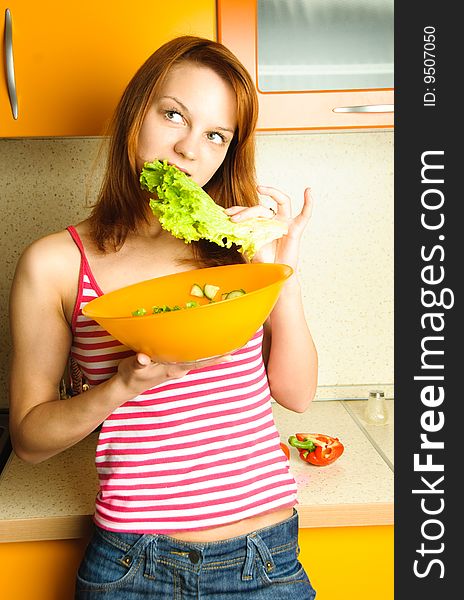 Beautiful young woman at home in the kitchen eating salad. Beautiful young woman at home in the kitchen eating salad