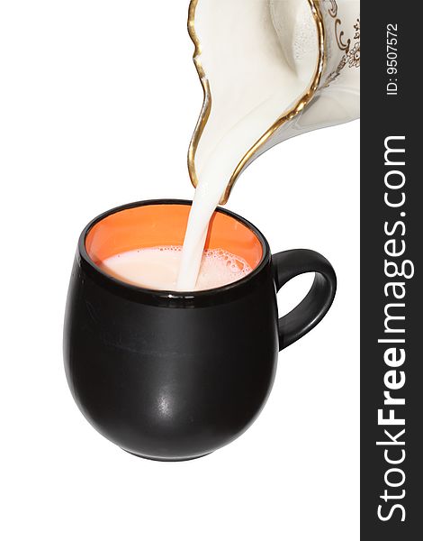 Milk pouring from pitcher into a black cup isolated with clipping path. Milk pouring from pitcher into a black cup isolated with clipping path