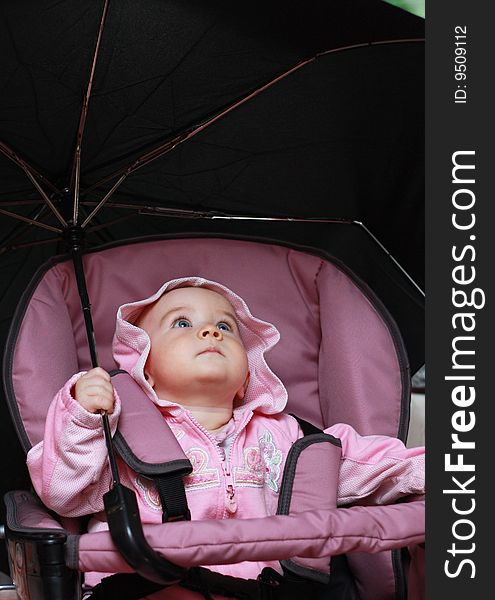 Baby sitting in a pram and holding a large umbrella. Baby sitting in a pram and holding a large umbrella