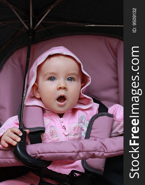 Baby sitting in a pram and holding a large umbrella. Baby sitting in a pram and holding a large umbrella