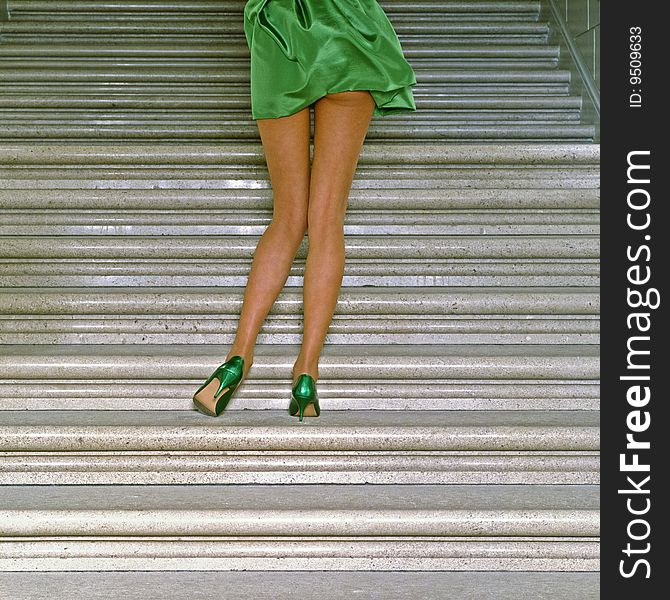 Young womans legs with green miniskirt and green high heels on a marble staircase. Young womans legs with green miniskirt and green high heels on a marble staircase