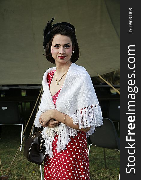 A woman with a 20s outfit including a polka dot dress and white shawl. A woman with a 20s outfit including a polka dot dress and white shawl.