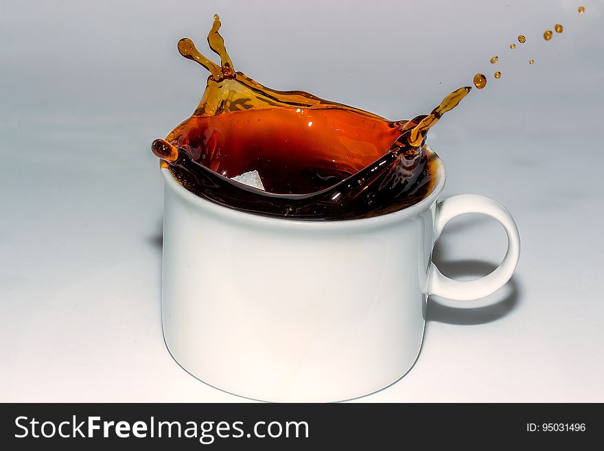 Coffee Splashing in Cup Against White Background