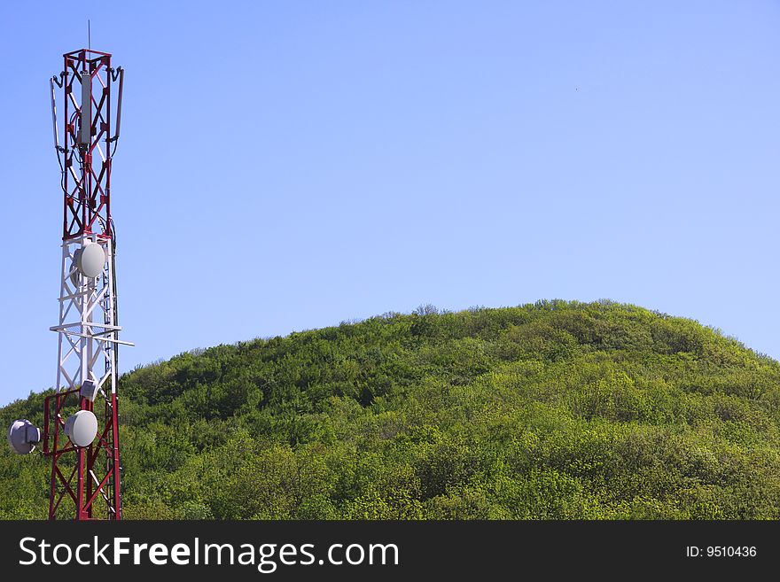 Telecommunication tower over blue sky and forest background