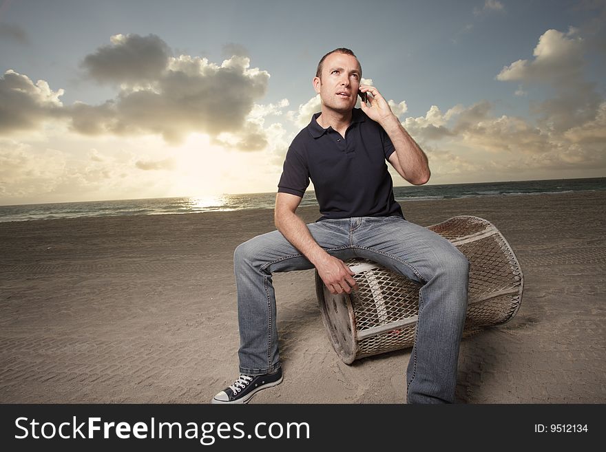 Handsome young man on the beach with a cellphone to his ear. Handsome young man on the beach with a cellphone to his ear
