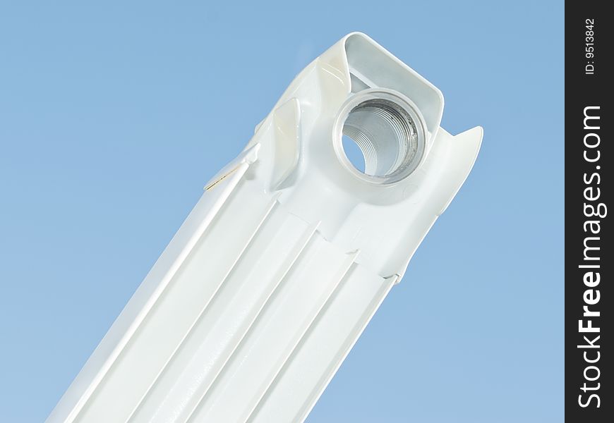 White radiator segment without valve on the blue sky background. White radiator segment without valve on the blue sky background