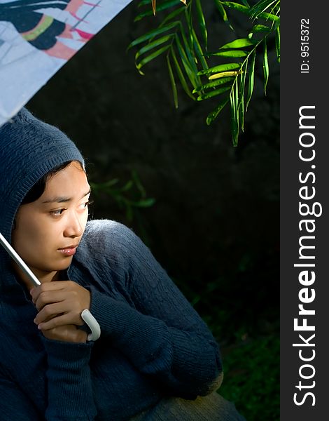 Portrait of asian woman on her sweater and holding an umbrella on a cold and rainy night. seems to worry of something and feeling insecure of her current circumstances. Portrait of asian woman on her sweater and holding an umbrella on a cold and rainy night. seems to worry of something and feeling insecure of her current circumstances.