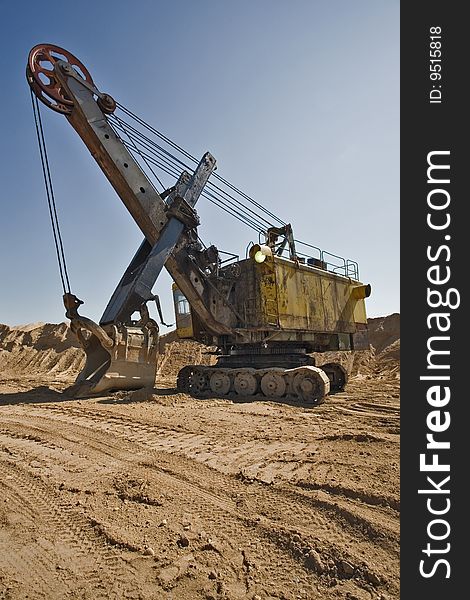 Rusty old yellow excavator on a sand