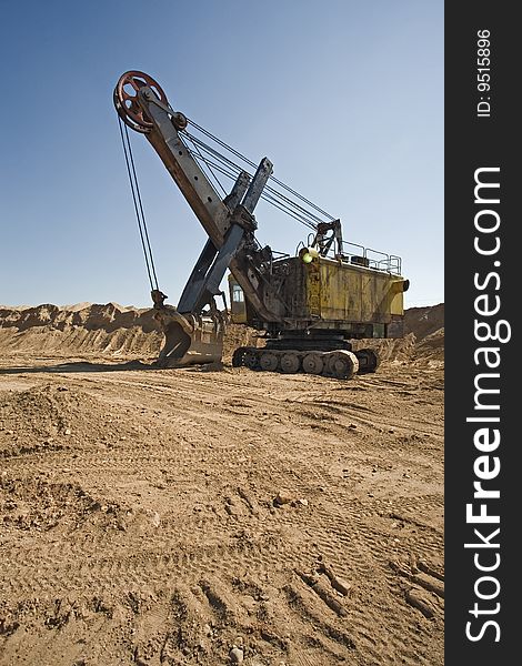 Rusty old yellow excavator on a sand