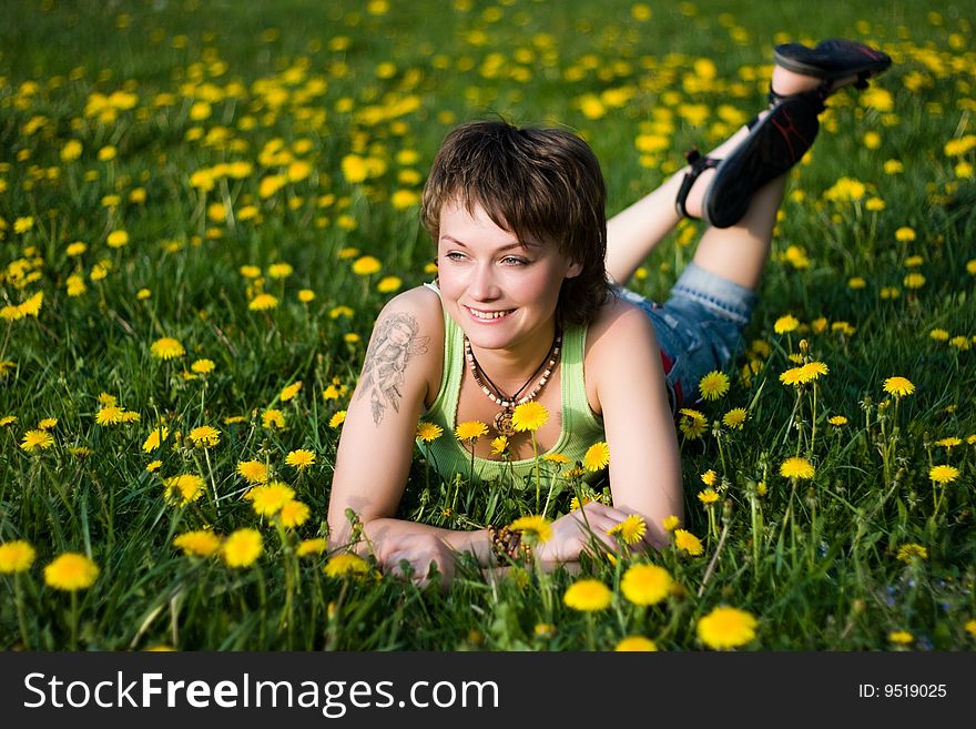 A young cheerful woman having fun on a dandelions glade