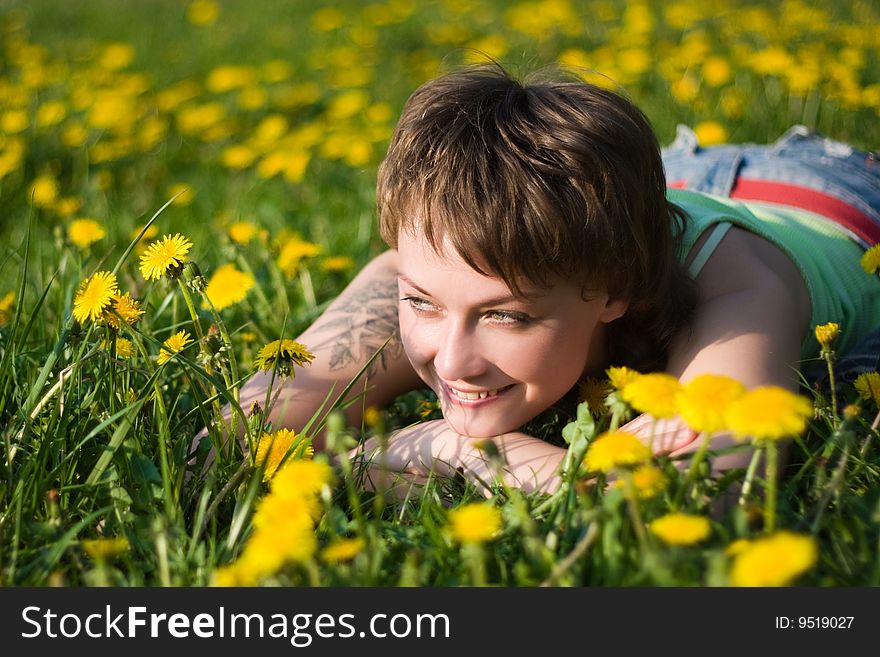 A young cheerful woman having fun on a dandelions glade