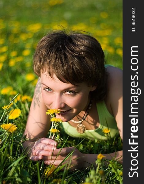 A young cheerful woman having fun on a dandelions glade