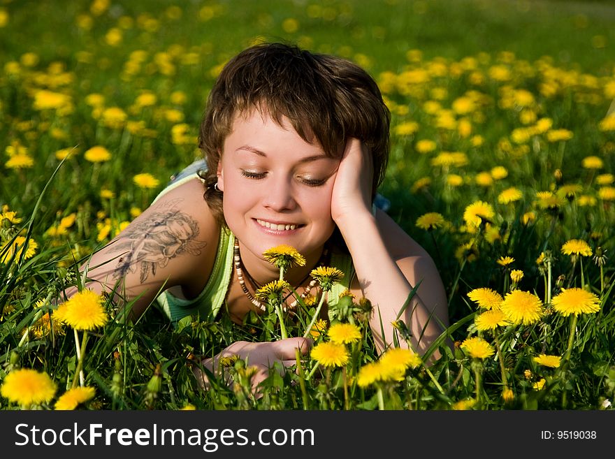 A young cheerful woman having fun on a dandelions glade