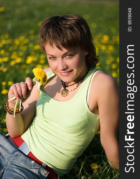 A young cheerful woman having fun on a dandelions glade