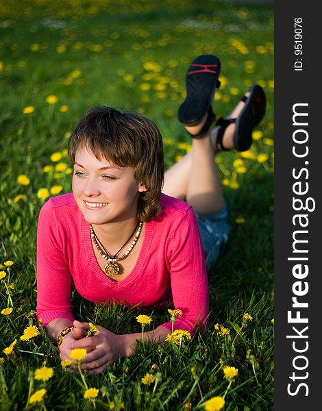 A young cheerful woman having fun on a dandelions glade