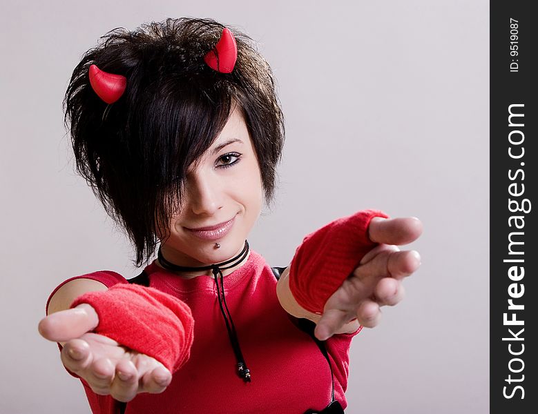 A young sexual girl in an image of a devil  in red and black with  horns on her head posing on a light background. A young sexual girl in an image of a devil  in red and black with  horns on her head posing on a light background