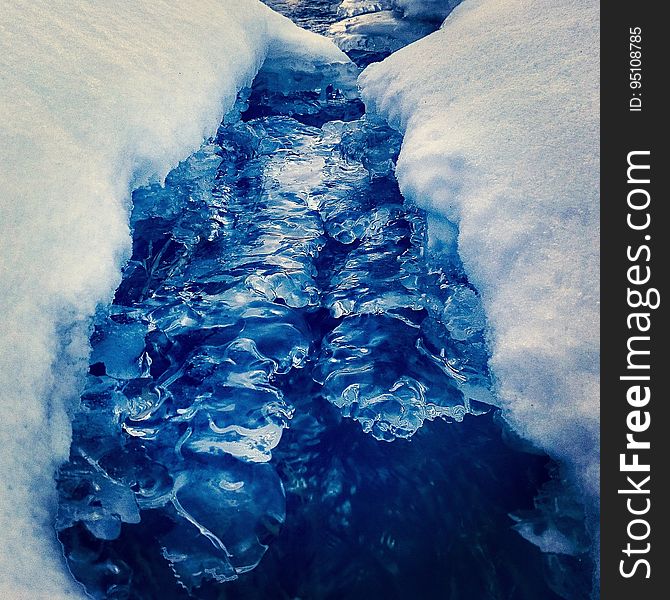 Closeup of a glacier crevasse filled with water.