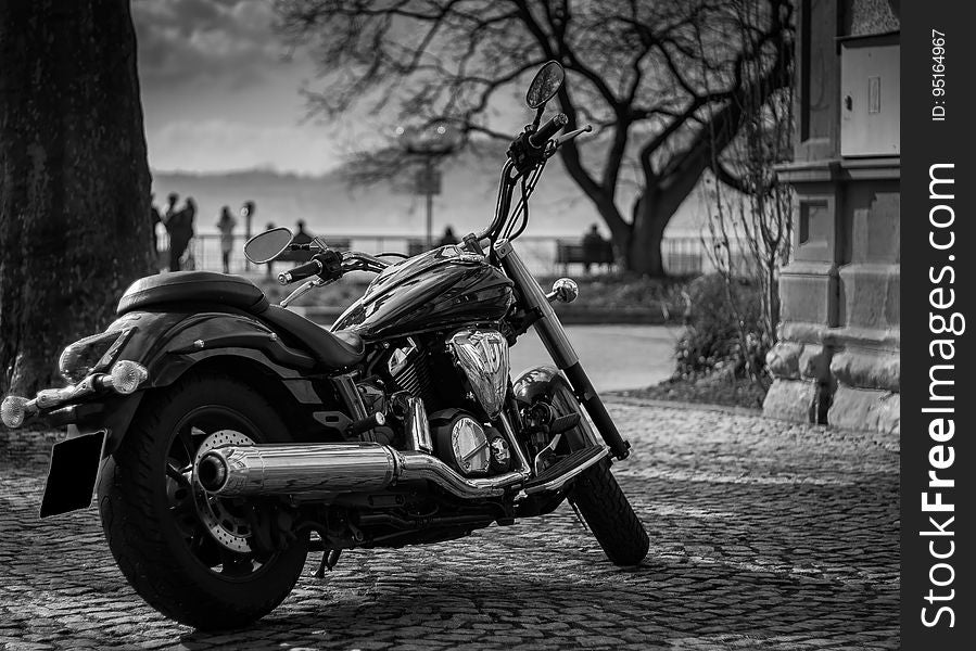A motorcycle parked on a street in black and white photo. A motorcycle parked on a street in black and white photo.