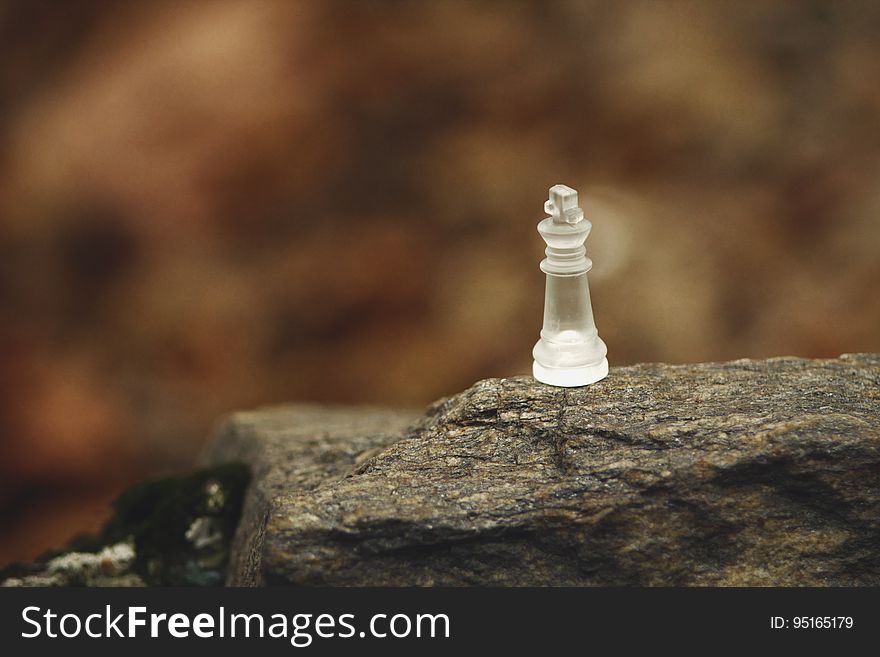 A close up of a glass chess piece on a rock. A close up of a glass chess piece on a rock.
