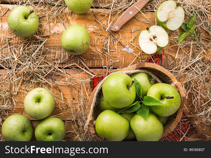 Green apples on wood background with dry grass.