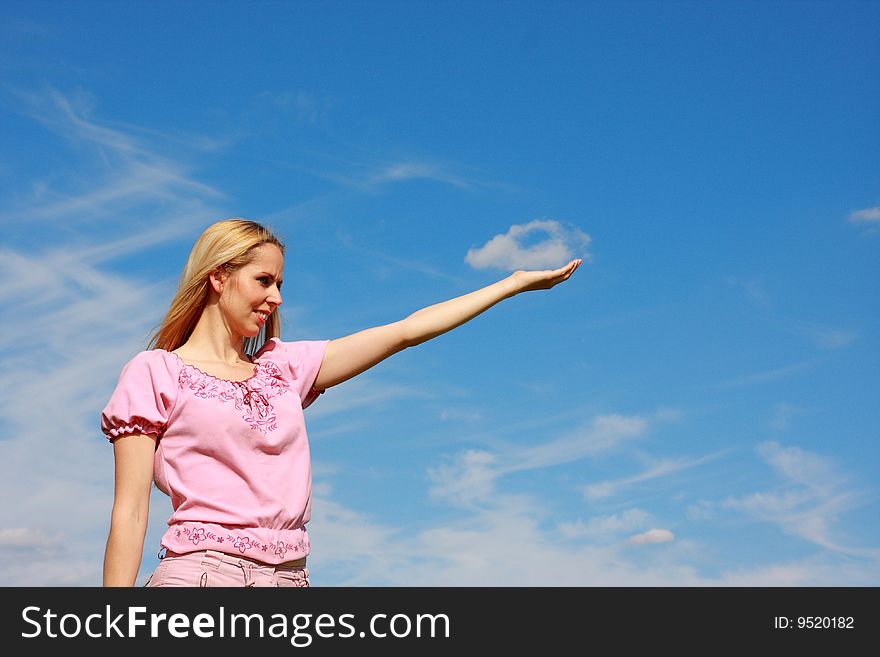 Blond female holding cloud in hand over blue sky. Blond female holding cloud in hand over blue sky