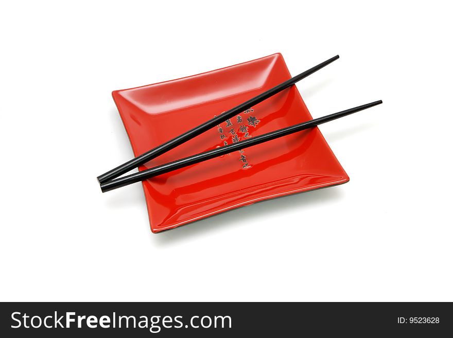 Chopsticks on  red square plate with kanji inscription isolated. Chopsticks on  red square plate with kanji inscription isolated