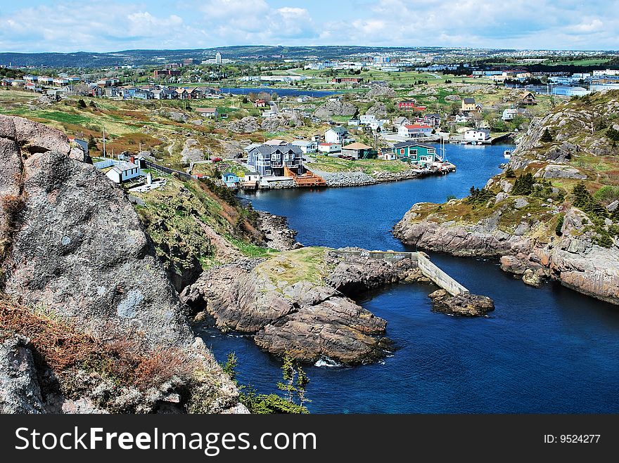 Aerial view of town on rocky coastline with inlet in foreground.