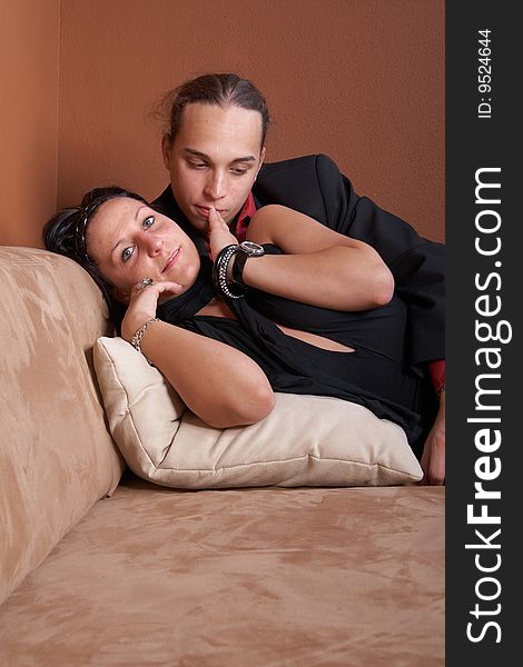 Young couple cuddling on a couch at home coming back from a party. Young couple cuddling on a couch at home coming back from a party.