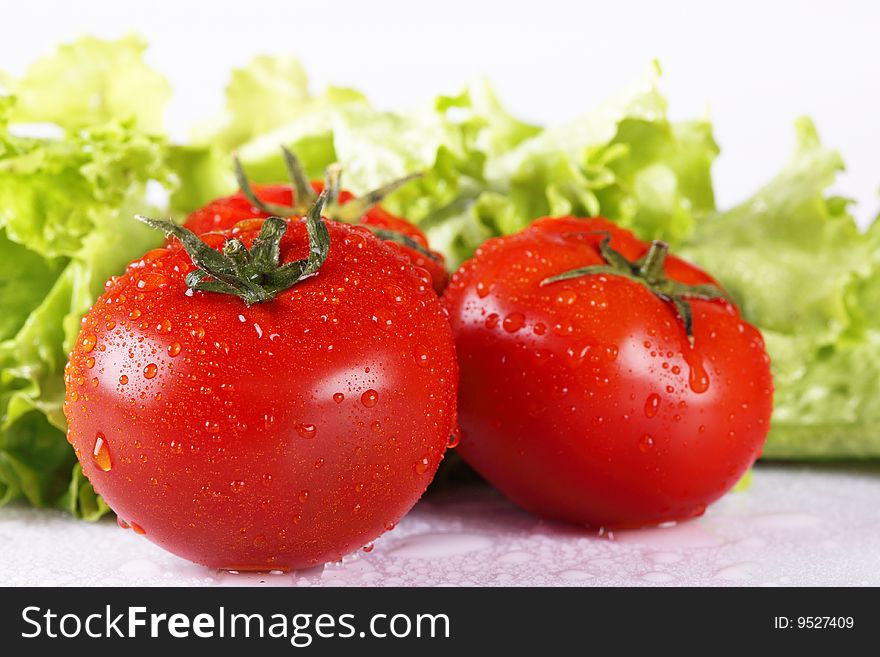 Two red fresh tomatoes and salad leaves