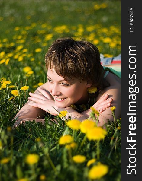 A young cheerful woman having fun on a dandelions glade