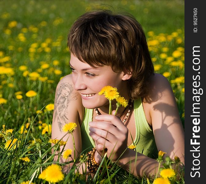 A young cheerful woman having fun on a dandelions glade