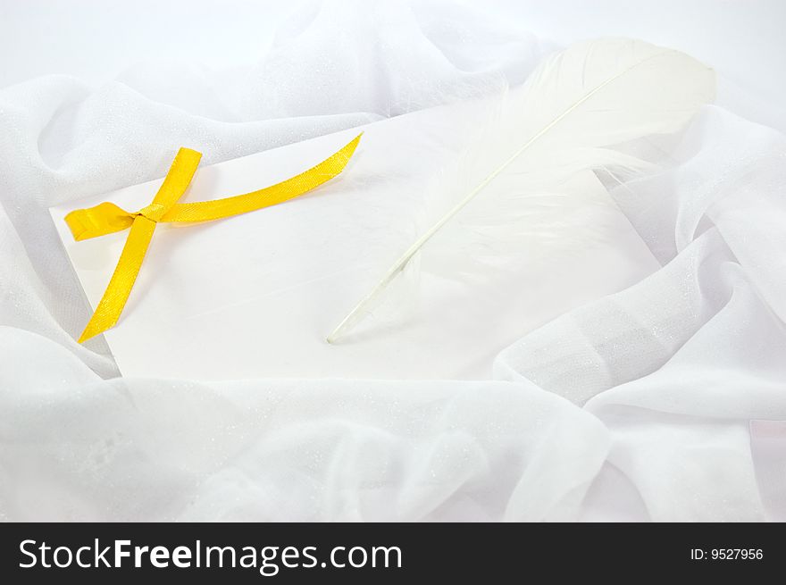 Blank note, yellow ribbon and feather to write over white fabric