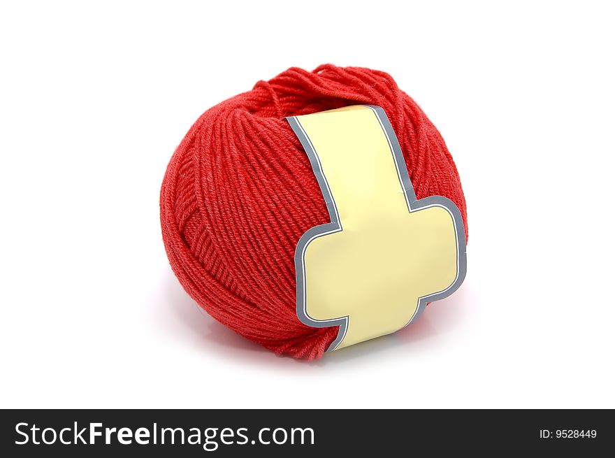 Ball of a red wool with yellow label. White background.