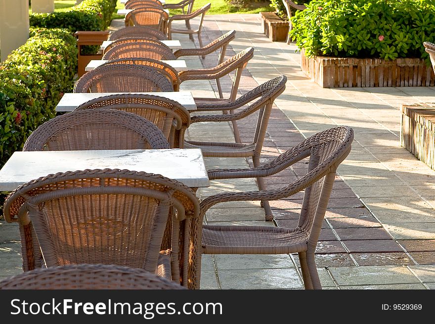 Table and four chairs on patio near bush and grass