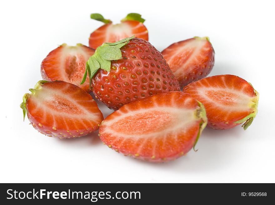 Whole strawberry and the berries of a strawberry cut on halves. A photo close up.